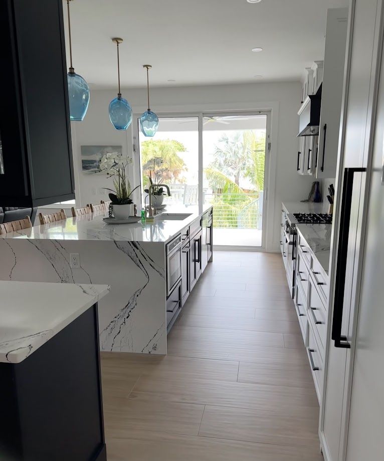 Freshly cleaned Sarasota kitchen with marble island and glass pendant lights